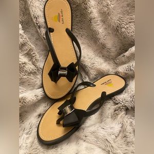 Flat black, hard soled flip flops with bows